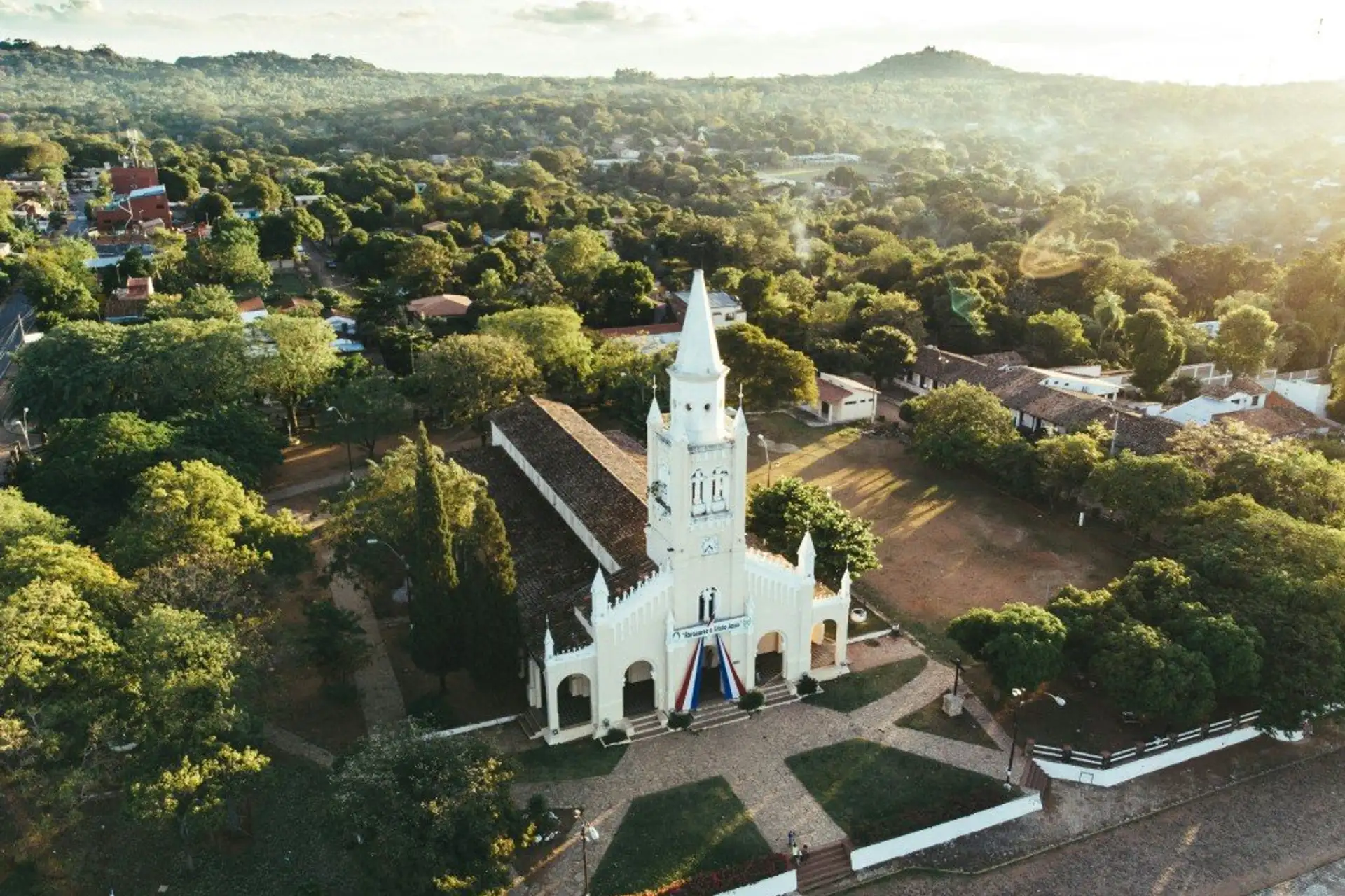 Aerial view of the white church and town of Aregua surrounded by hills and trees