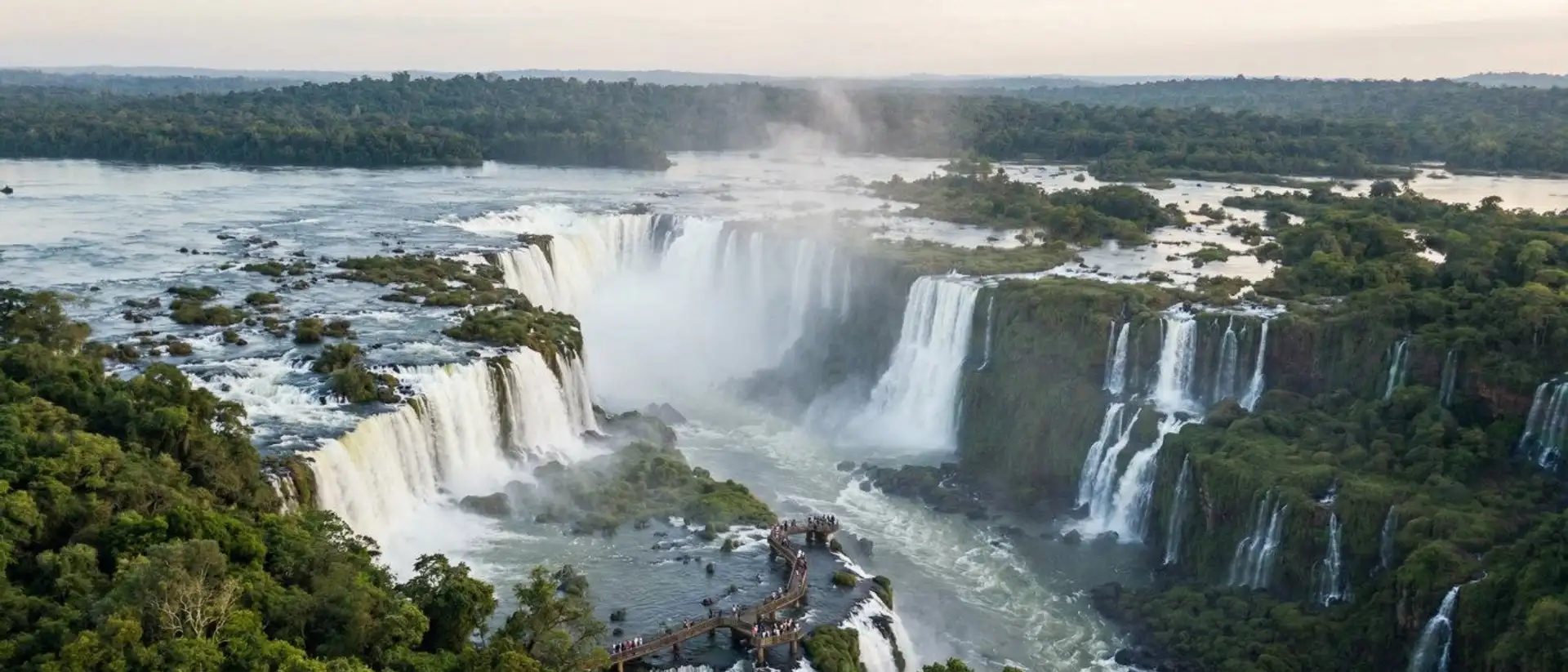 Aerial panorama of the wide cascading Iguazu Falls surrounded by rainforest