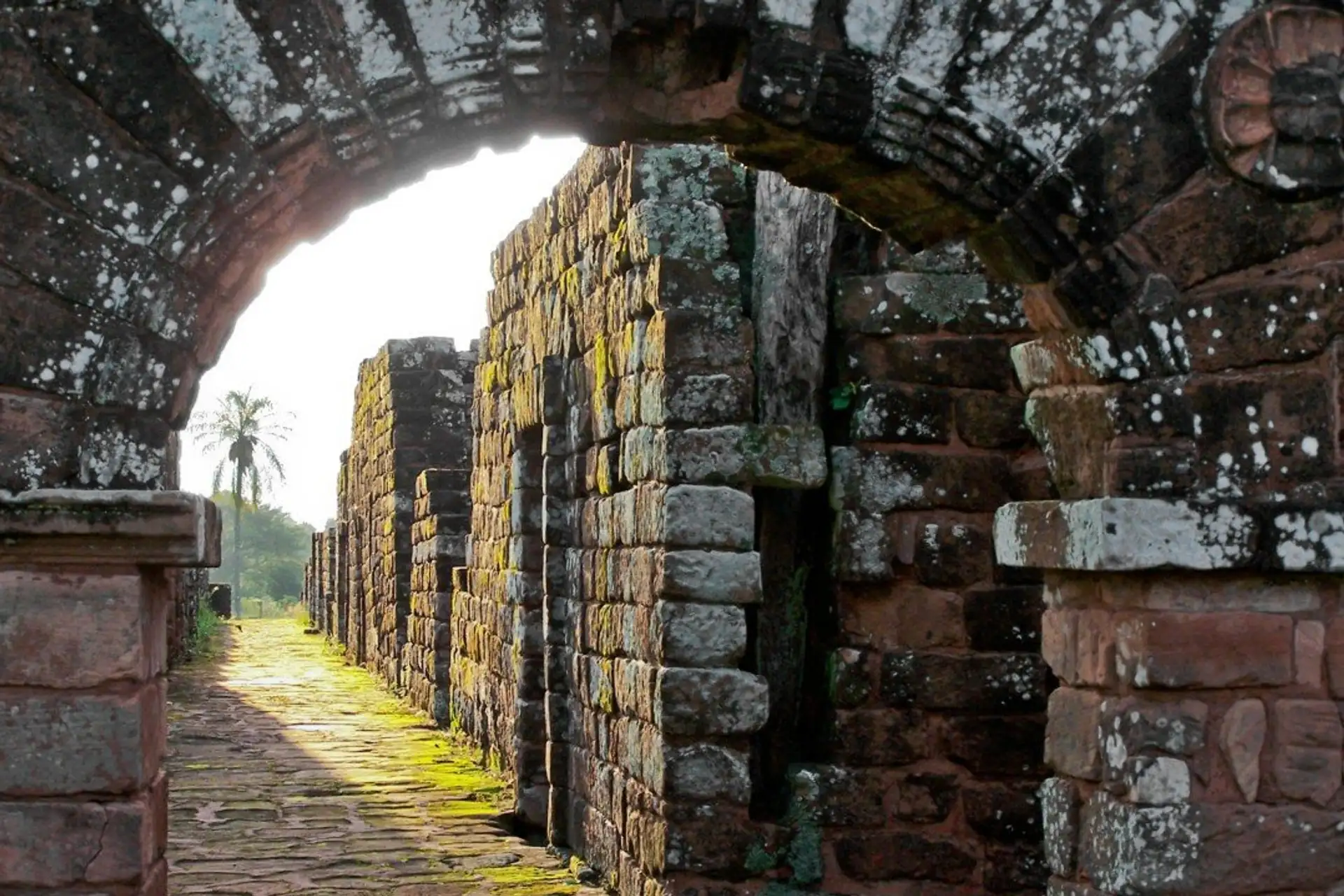 Stone archway leading into the moss covered walls of a Jesuit mission ruin